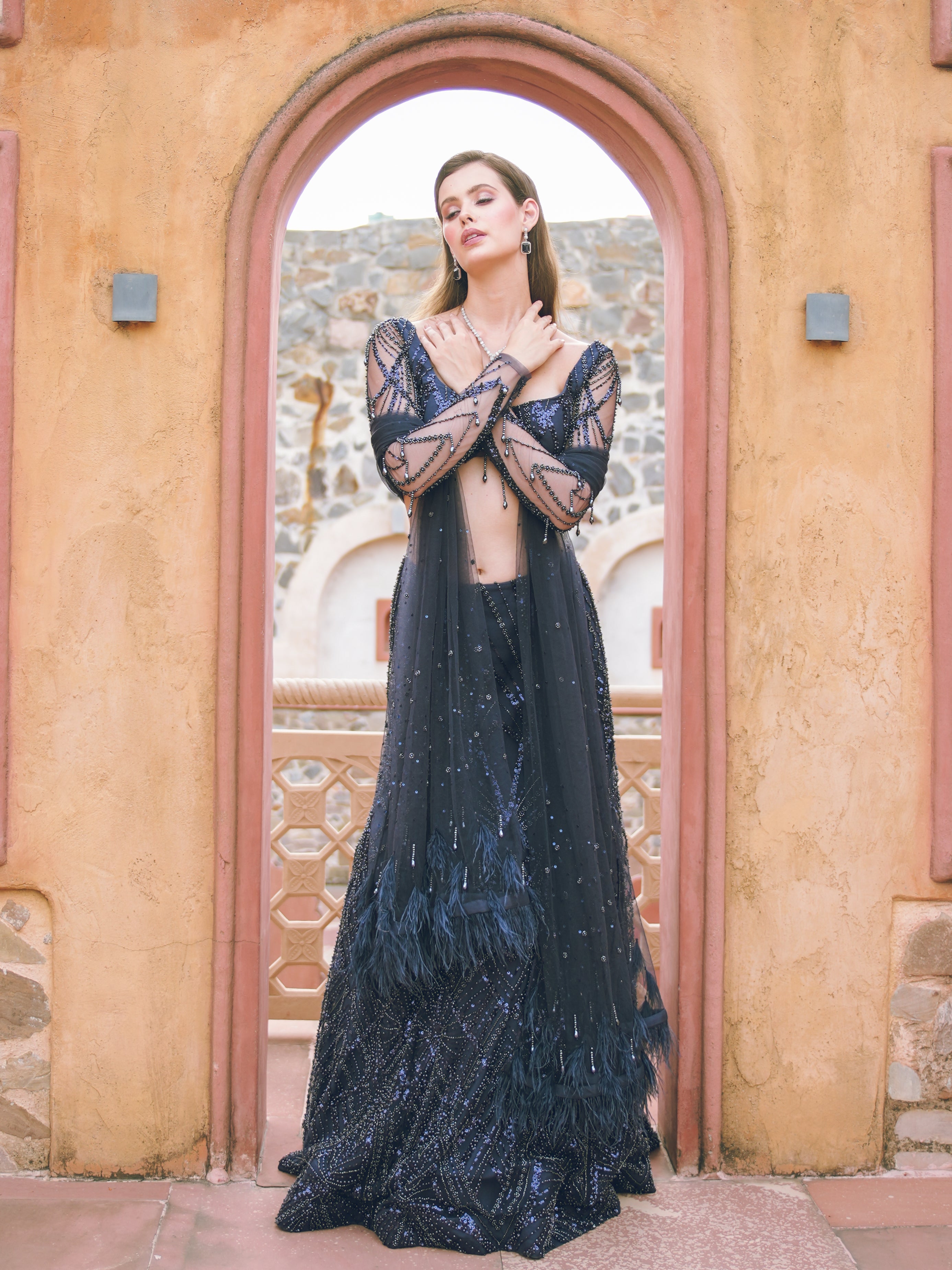 Woman in a dark blue evening gown standing in front of an archway.
